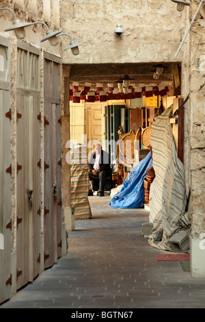 Un commerçant à l'extérieur de son magasin sur une ruelle à Souq Waqif, Doha, Qatar. Banque D'Images