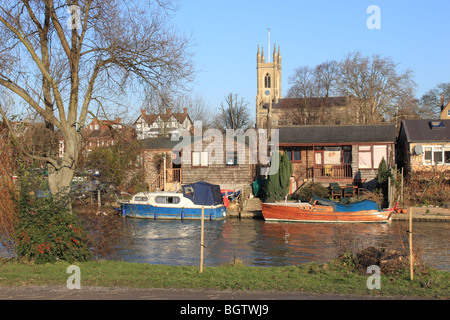 Des bateaux et des maisons de vacances sur l'île de Garrick's Aci, Tamise, East Molesey, Angleterre, Royaume-Uni, Europe. Hampton church de l'autre côté de la rivière en arrière-plan. Banque D'Images