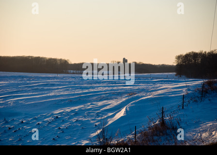 Des congères dans une prairie bordée d'une coloration bleue en fin d'après-midi. Banque D'Images