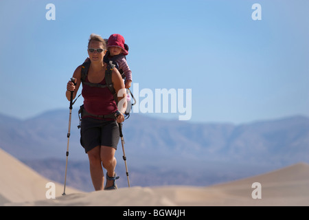 Female hiker carrying child piggy-back dans le désert, la Death Valley National Park, California, USA Banque D'Images