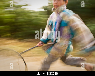 Un jeune garçon courir et jouer avec son bâton fait maison et hoop bidule le long du circuit trekking Helambu, au Népal. Banque D'Images