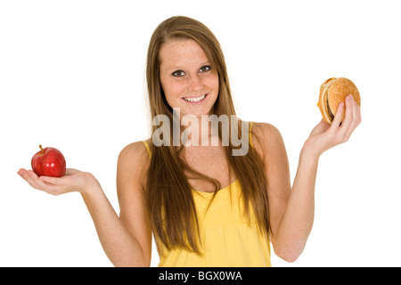 Caucasian woman holding an apple et hambuger essayant de décider lequel de manger Banque D'Images