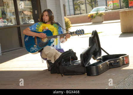 Photo montre un artiste de rue qui joue de la guitare et chanter à l'extérieur, sur un coin de rue, guitare case ouvert aux contributions. Banque D'Images