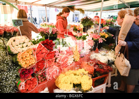 PARIS, France — Un marché parisien en plein air dynamique présente une gamme de produits frais. Les fruits et légumes colorés sont agencés avec art dans divers stands, tandis que les vendeurs et les acheteurs locaux interagissent dans cette scène traditionnelle du marché français. Banque D'Images