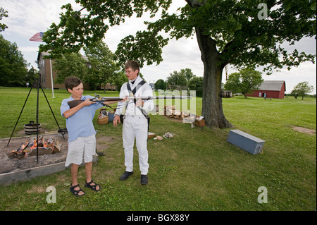 Teen boy holding Guerre de 1812 reenactor's mousquet. Banque D'Images