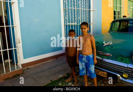 Deux enfants avec portées 1958 Chevy classique sur rue pavée de carré central de Trinidad Cuba une vieille ville coloniale Banque D'Images