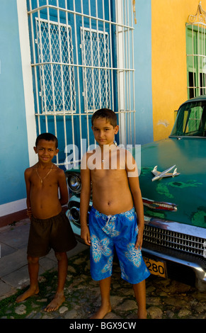 Deux enfants avec portées 1958 Chevy classique sur rue pavée de carré central de Trinidad Cuba une vieille ville coloniale Banque D'Images