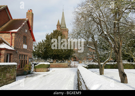 Village de Aldford, Angleterre. Compte tenu de l'hiver en milieu rural village store avec St Jean Baptiste l'église de l'arrière-plan. Banque D'Images