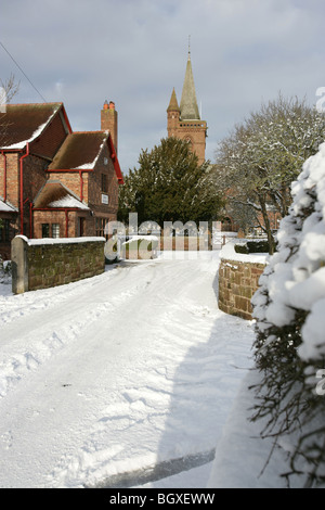 Village de Aldford, Angleterre. Compte tenu de l'hiver en milieu rural village store avec St Jean Baptiste l'église de l'arrière-plan. Banque D'Images