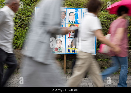 Les piétons passent devant les affiches des candidats du parti politique, de la publicité leur candidature pour les élections de la ville de Tokyo. Banque D'Images