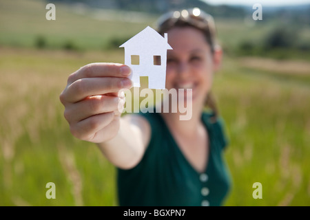 Woman raising cut-out paper house Banque D'Images