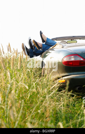 Pieds d'un couple qui le de la voiture Banque D'Images