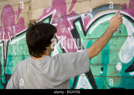 Jeune homme peinture par pulvérisation murale graffiti Banque D'Images