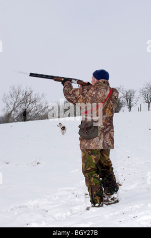 Le tournage d'un homme sur un fusil alésage 12 Pheasant shoot dans la neige. Banque D'Images