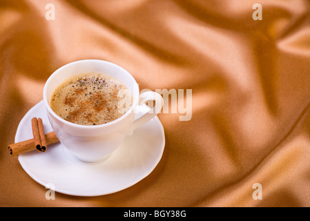 Tasse de café aromatique et deux morceaux de bâtons de cannelle sur fond doré Banque D'Images