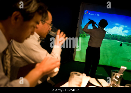 Les clients salarymen japonais boire des bières et jouer au golf informatisé,dans un bar Golf, Tokyo, Japon. Banque D'Images