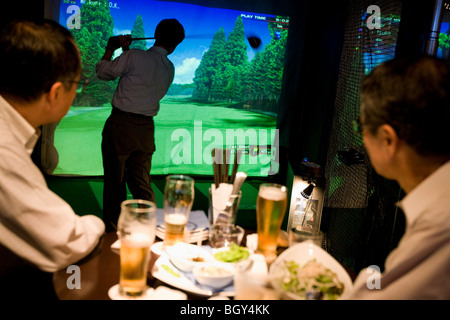 Les clients salarymen japonais boire des bières et jouer au golf informatisé,dans un bar Golf, Tokyo, Japon. Banque D'Images