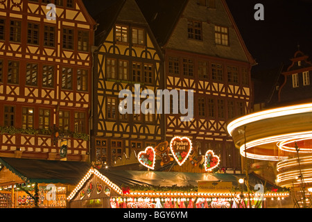 Lumières des étals de marché et merry-go-round pendant les marchés de Noël à la place de l'Hôtel de Ville (Römerberg) dans la ville de Banque D'Images