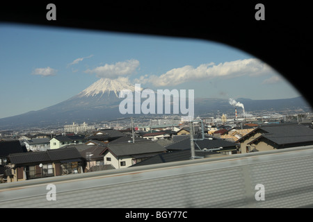 Le Mont Fuji, vu derrière un fond de paysage agricole et industriel, d'un shinkansen train à grande fenêtre, le Japon. Banque D'Images