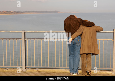 Un couple sur le quai d'un jour brumeux, à Southwold, Suffolk , Angleterre , Angleterre , Royaume-Uni Banque D'Images