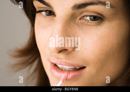 Young woman applying lip-gloss avec pinceau à lèvres Banque D'Images