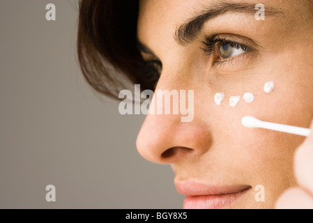 Young woman applying undereye cream Banque D'Images