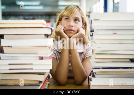 Jeune fille s'appuyant sur le coude rêverie, des piles de livres en premier plan Banque D'Images