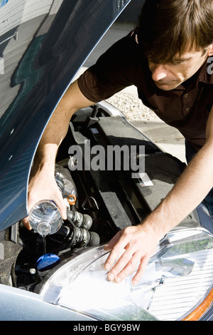 Homme verser de l'eau dans le radiateur de voiture surchauffée Banque D'Images
