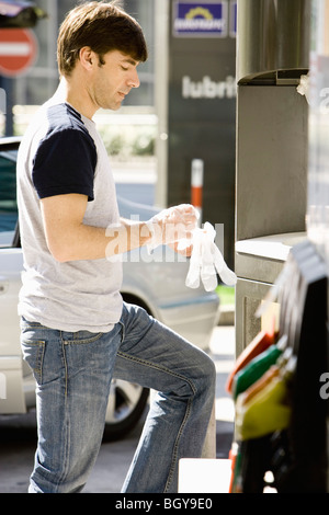 Man at gas station puttong gants jetables sur la préparation pour faire le plein de véhicule Banque D'Images
