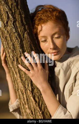 Woman embracing arbre, les yeux fermés Banque D'Images