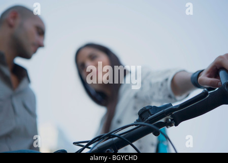 L'homme et la femme d'avoir une conversation, femme tenant un guidon de vélo Banque D'Images