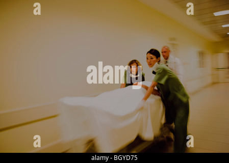 Les travailleurs de la santé rushing patient on gurney in hospital corridor Banque D'Images