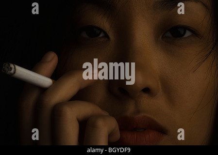Woman holding up cigarette allumée, close-up Banque D'Images