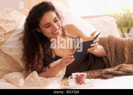 Woman Reading a book in bed Banque D'Images