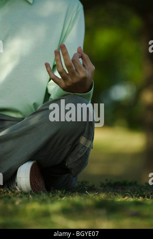 Homme assis sur l'herbe dans la position du lotus, cropped Banque D'Images