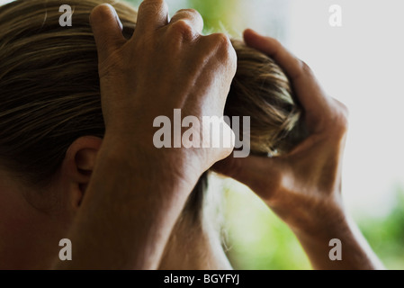 Personne styling woman's hair, cropped Banque D'Images