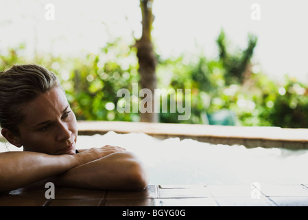 Femme dans la piscine, resting head on arms Banque D'Images