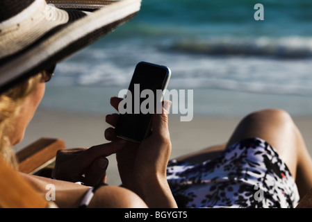 Woman text messaging with smartphone at beach Banque D'Images