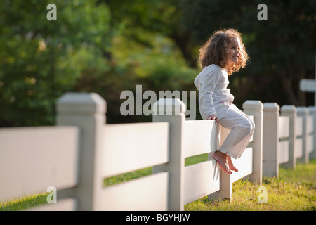 Girl sitting on fence Banque D'Images