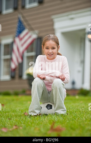 Girl sitting on soccer ball Banque D'Images