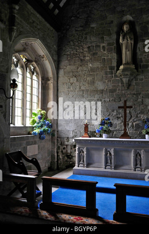 Soleil brillant à travers la fenêtre de l'église ornée pour briller sur la croix, l'alter et l'affichage de fleurs dans Stourhead Wiltshire Banque D'Images