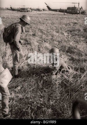 Les soldats de l'armée du Sud Vietnam attendre dans un champ près de helicopters de la 121e compagnie d'hélicoptères d'assaut dans le Delta du Mékong. Banque D'Images