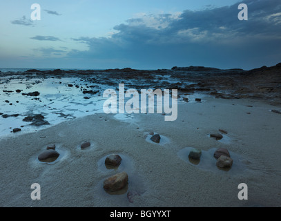 Petits rochers une large place sur le sable comme un orage d'été passe, Wollongong, NSW Australie Banque D'Images