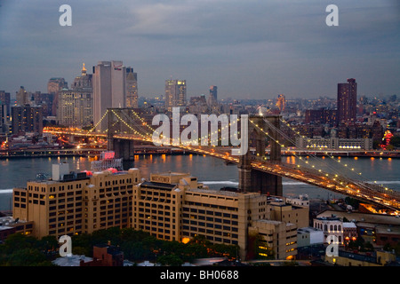 L'éclat des lumières au crépuscule dans la partie basse de Manhattan et de New York City's Pont de Brooklyn. Banque D'Images