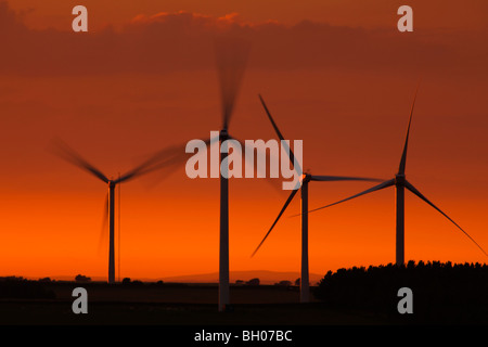 Quatre éoliennes contre ciel dramatique au coucher du soleil Banque D'Images