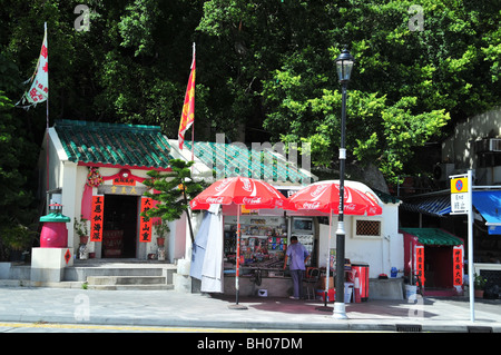 Tai Wong de culte avec les drapeaux de prières, à côté d'un commerçant vendant des boissons, magazines, Promenade, Stanley Stanley, Hong Kong, Chine Banque D'Images