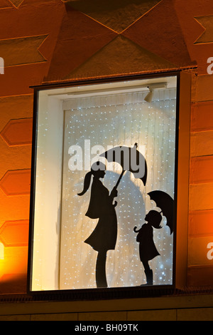 Affichage vitrine montrant une silhouette d'une femme et de la jeune fille qui détiennent chacun un parapluie dans la Ville de München (Munich), la Bavière Banque D'Images