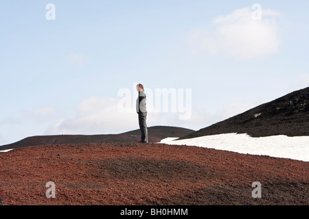 Femme debout dans la lave sur une colline, hautes terres d'Islande Banque D'Images
