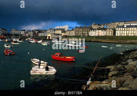 Les garçons sur les bateaux au port sous de sombres nuages, Portrush, comté d'Antrim, Irlande, Europe Banque D'Images