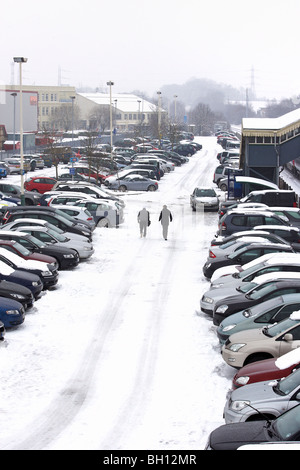 Deux personnes entrent par une gare parking après les tempêtes d'hiver a frappé le Royaume-Uni. Banque D'Images